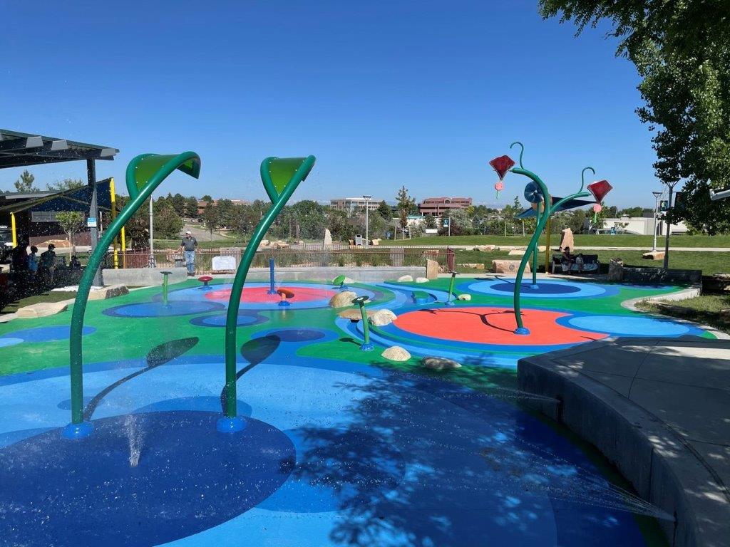 Children playing at a splash pad and playground at Centennial Center Park